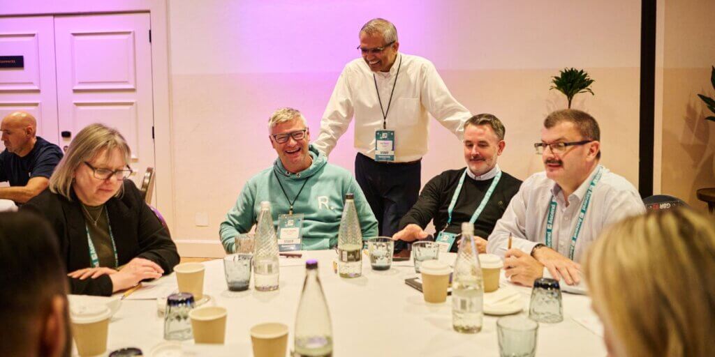 Resolver president kam rawal stands smiling with attendees during a roundtable at ascend grc london 2025, fostering peer collaboration.