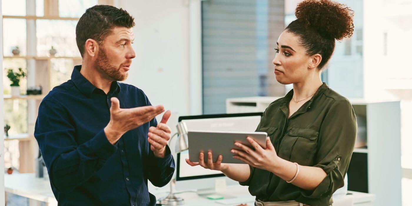 Two professionals discussing risks facing the hospitality industry while reviewing data on a tablet.