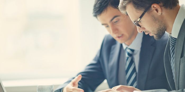 Two men in suits looking at reports representing challenges faced when implementing an erm program