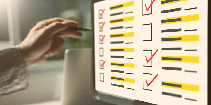 Male hand holding pen pointing at computer screen with checklist representing erm maturity assessment